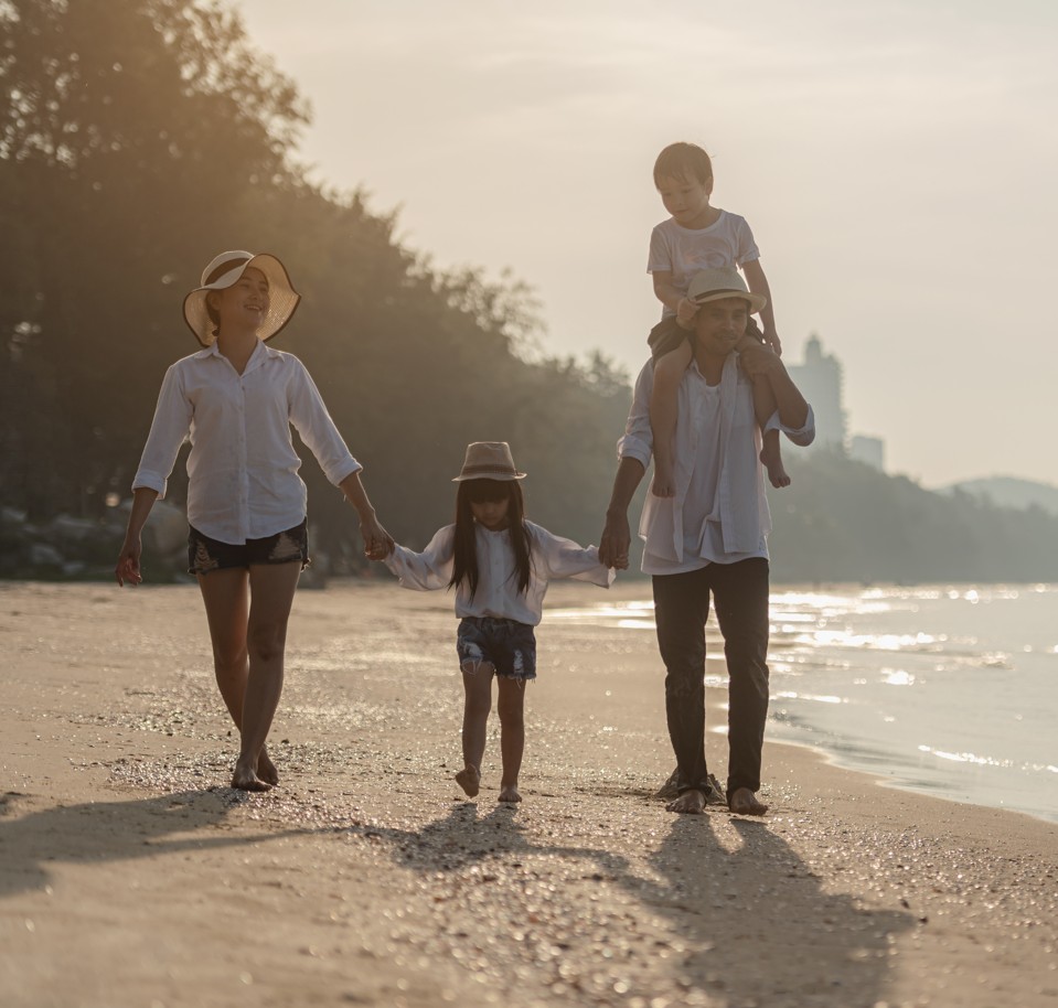 Famille deux parents deux enfants marchant au bord de plage, coucher de soleil